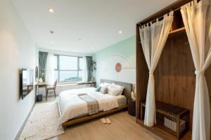头顿THE SONG VŨNG TÀU - Five-Star Luxury Apartment - Căn Hộ Du Lịch 5 Sao Cạnh Biển的一间卧室配有一张大床和一张书桌