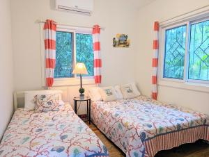 罗阿坦West Bay Roatan - Sunny & Modern Oasis- 2 Bedrooms - 3 min walk to beach的一间卧室设有两张床和两个窗户。