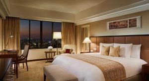 上海上海波特曼丽思卡尔顿酒店的酒店客房设有一张大床和一张书桌。