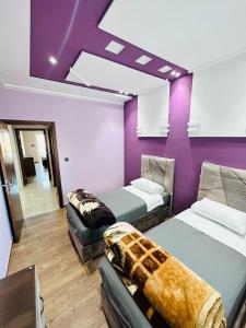 拉腊什Abraj Dubai Larache的一间设有两张床和紫色墙壁的客房