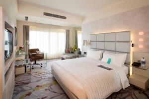古尔冈古尔冈铂尔曼中央公园酒店的酒店客房设有一张大床和一张书桌。