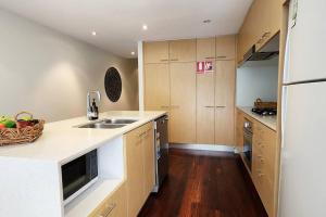 悉尼Stylish parkside retreat的厨房配有木制橱柜、水槽和柜台。