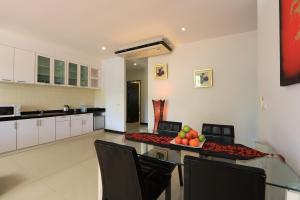 拉威海滩Rawai Grand House -SHA Plus的厨房配有桌椅和一碗水果