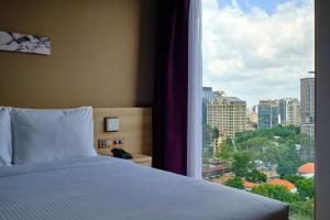 胡志明市Sotetsu Grand Fresa Saigon 相鉄グランドフレッサ サイゴン的一间卧室设有一张床和一个大窗户