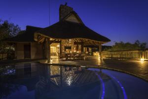 威尔吉旺登禁猎区Tshwene Lodge的夜间带游泳池和凉亭的度假村
