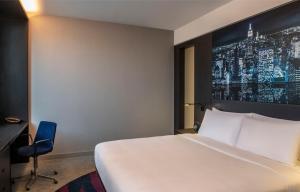 迪拜Aloft Dubai Creek的卧室配有一张白色大床和一把椅子