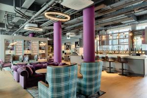 沃尔夫斯堡Premier Inn Wolfsburg City Centre的大堂设有紫色的沙发和桌子,酒吧