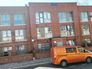 伦敦Cosy Two Bedroom Apartment的停在砖楼前的橙色货车