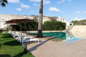 萨尔加AluaSoul Menorca - Adults Only的一个带躺椅和遮阳伞的游泳池