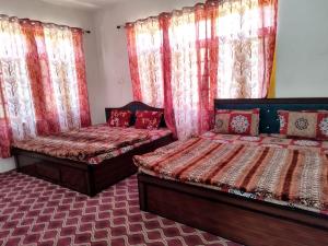 斯利那加Hotel city way的配有红色窗帘的客房内的两张床