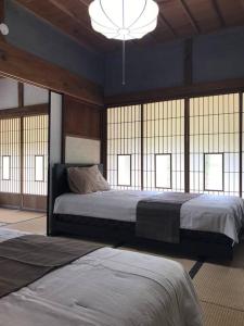 Inashikiビラ里山双林的一间卧室设有两张床、一个吊灯和窗户。