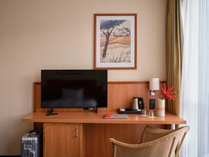 不莱梅不莱梅城际酒店的一间配有电视的房间,桌子上配有两把椅子