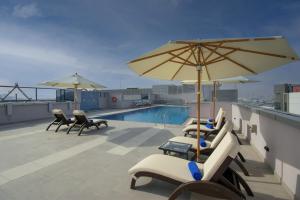 迪拜Jood Hotel Apartments的一个带椅子和遮阳伞的庭院和一个游泳池