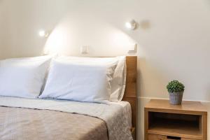 阿吉奥斯普罗科皮奥斯Naxian Place 2的一张带白色枕头的床和一张桌子上的植物