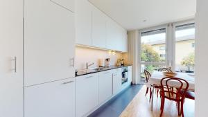 蒙特勒Bright flat overlooking Lake Geneva的厨房配有白色橱柜和桌椅