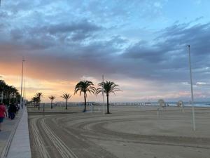 甘迪亚海滩Apartament Bari Playa的日落时分拥有棕榈树和海洋的海滩