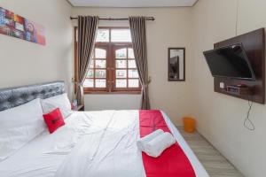 巴图RedDoorz at WR Supratman Batu的一间卧室配有一张带红色和白色床罩的床。