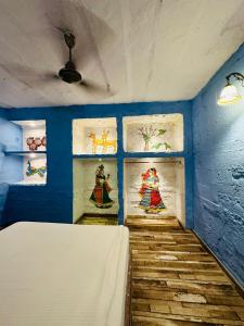 焦特布尔拉尼泰姬陵酒店的蓝色客房的墙壁上装饰有绘画作品