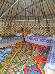 TongGuest house and Yurt camp "Ailuu"的圆顶帐篷内带两张床和地毯的房间