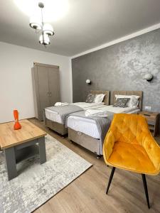 德瓦Burebista Residence的一间卧室配有两张床、一张桌子和一把椅子