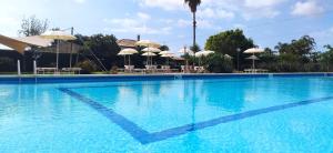 锡拉库扎休闲酒店的一个带遮阳伞和桌子的大型蓝色游泳池