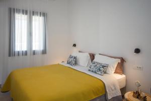 米克诺斯城Alko Apartments的一间卧室配有一张带黄色毯子和枕头的床。