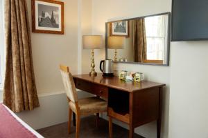 伊利Lamb Hotel by Greene King Inns的一张位于酒店客房内的桌子,配有镜子和椅子