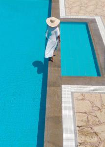 锡蒂亚Oceanides Luxury Apartments的戴帽子的人站在游泳池旁