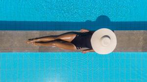 锡蒂亚Oceanides Luxury Apartments的戴帽子的女人在游泳池游泳