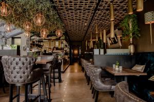 克拉科夫Art Suites Luxury Hotel的一间带桌椅的餐厅和一间酒吧