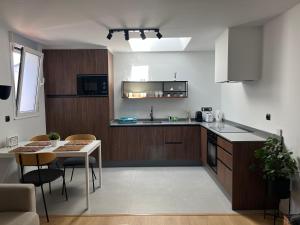 蓬费拉达Bierzo Habita Apartments的厨房配有木制橱柜和桌椅