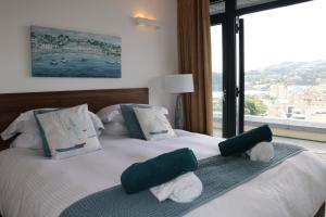 廷茅斯Riviera Apartments - Five Stylish Penthouse Apartments with Unrivalled Sea Views of Teignmouth, Shaldon, The Jurassic Coastline & The Teign Estuary的一间卧室配有带绿色和白色枕头的床