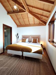 CoutoVerde Água Agroturismo e Agricultura Biológica的一间卧室设有一张大床和木制天花板