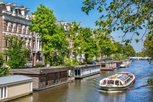 阿姆斯特丹Amstel Corner Hotel的一条在城市里沿着河流航行的船