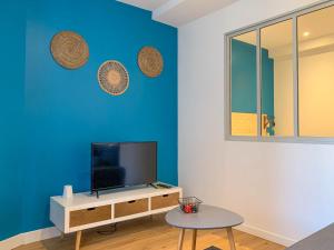 BuxyAmbiance Cosy的客厅配有电视和蓝色的墙壁