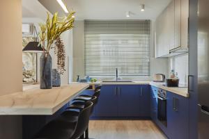 Káto YerakaríonGaladriel Apartments的厨房配有蓝色橱柜和带椅子的柜台。