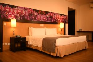 麦德林米桑迪尔格酒店的卧室配有一张大床,墙上挂有绘画作品