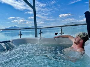 格伦科Beach Houses with Hot Tubs的男人在浴缸里喝一杯葡萄酒