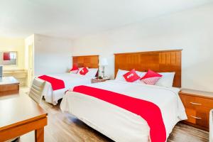 圣安东尼奥Oyo Hotel San Antonio Lackland AFB Seaworld Hwy 90 W的两张位于酒店客房的床,配有红色和白色床单