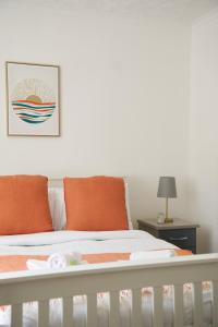格拉斯哥Rotherwood Apartment的卧室内带橙色枕头的白色婴儿床