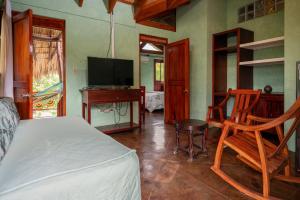 马萨亚庄园天堂之门生态屋水疗度假村的一间卧室配有一张床、一张书桌和一台电视