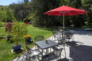 阿斯科纳Parkhotel Emmaus - Casa del Sole的一组桌椅,配有红色伞