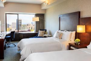 西雅图西雅图万丽酒店的酒店客房设有两张床、一张书桌和一个窗户。