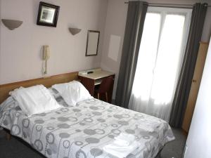 卢尔德Hotel Du Gave的一间卧室配有一张床、一张书桌和一个窗户。