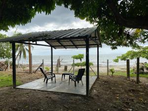 Punta de PiedraMalibu beach的海滩上带2把椅子和1张桌子的凉亭