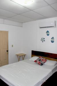 拉利伯塔德Kali Hostal的一间卧室配有白色床单和蓝色及白色墙壁。