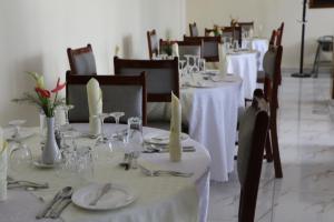 鲁亨盖里Fatima Hotel的一间用餐室,配有白色桌椅、盘子和餐巾