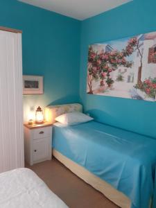 卡拉马孔Olive House的一间蓝色的卧室,配有一张床和墙上的绘画