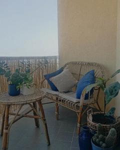 阿格里真托La Terrazza di Empedocle的柳条长凳坐在种植了盆栽植物的阳台