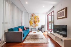 马德里Chueca Gran Via Recoletos Libertad 24 12的客厅配有蓝色的沙发和平面电视。